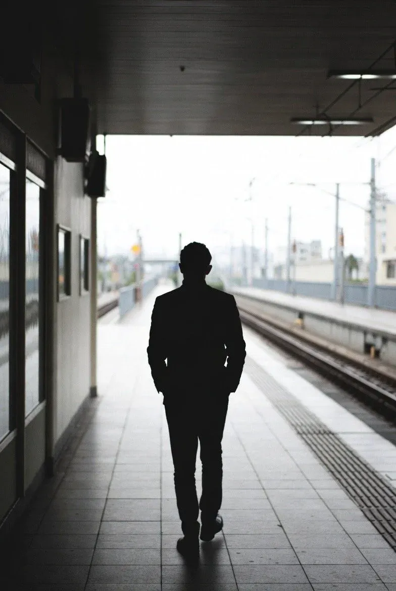 A lone businessman silhouetted on an empty train platform